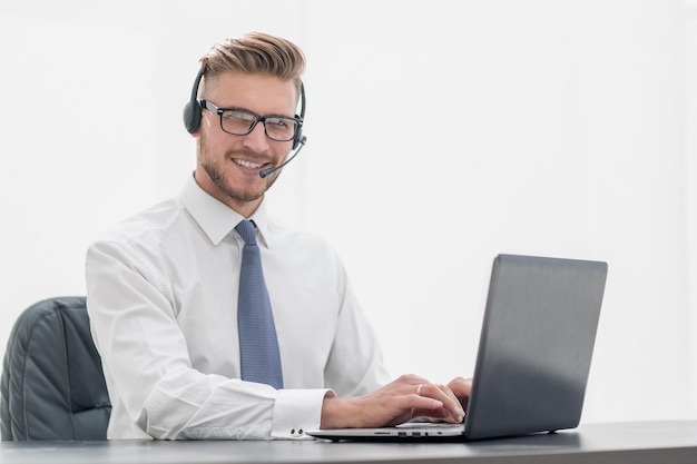 Hombre sonriente con auriculares trabajando en una laptopphoto con espacio de copia