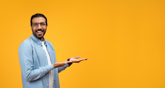 Foto un hombre sonriente con barba y gafas sostiene su mano plana y extendida