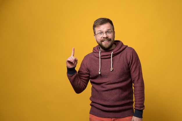 Foto un hombre sonriente y benévolo señala con el dedo que tiene una idea y se alegra, copia espacio