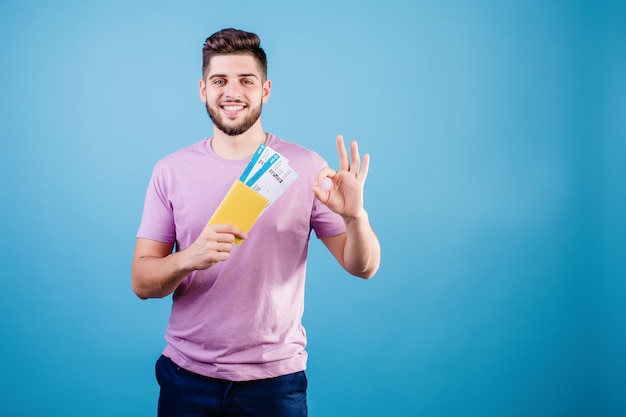 Hombre sonriente con boletos de avión y pasaporte aislado sobre azul