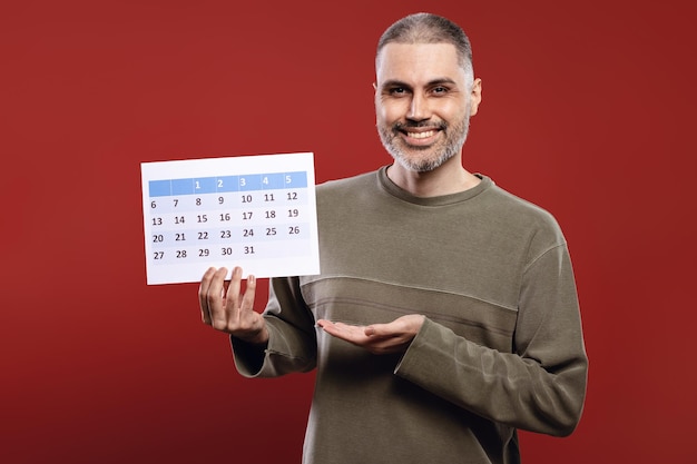 Foto hombre sonriente con un calendario de papel