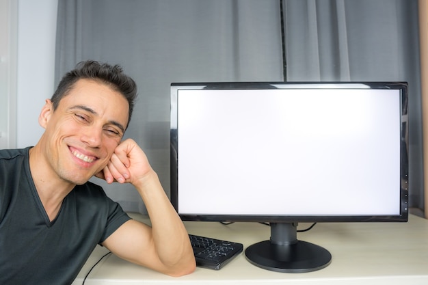 Hombre sonriente con camisa negra apuntando a una pantalla de computadora (copia de espacio) anunciando noticias importantes. De cerca.