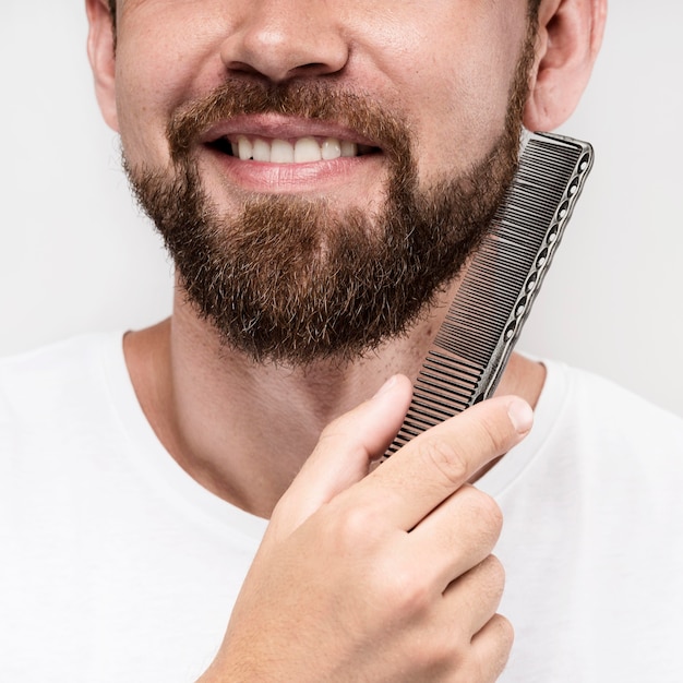 Foto hombre sonriente cepillándose la barba