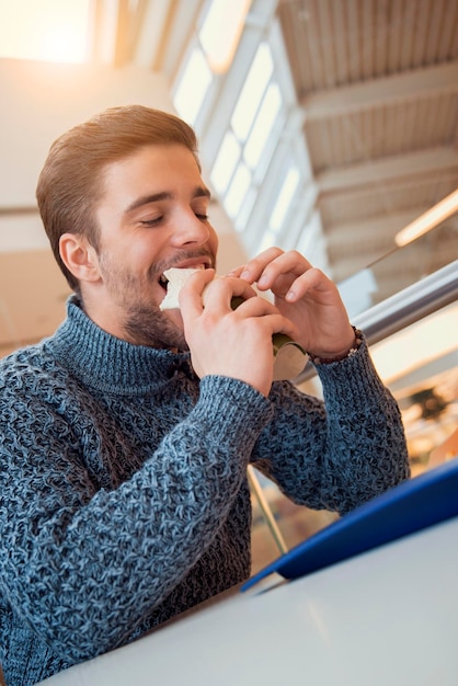 Hombre sonriente comiendo un sándwich