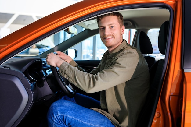 Un hombre sonriente conduce un auto nuevo Comprador feliz en el concesionario