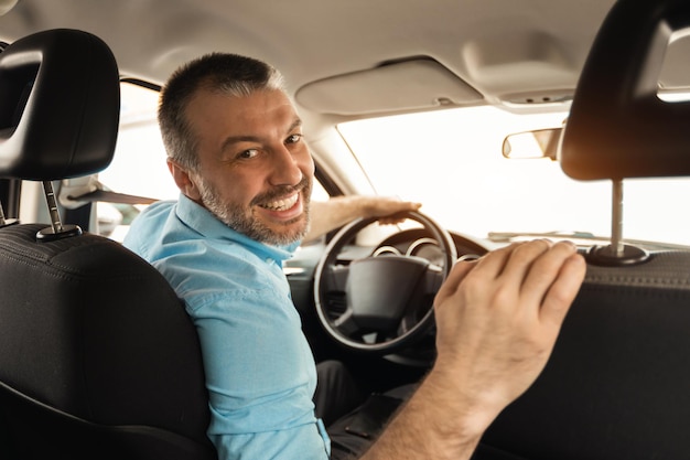 Hombre sonriente conduciendo un coche nuevo en la ciudad