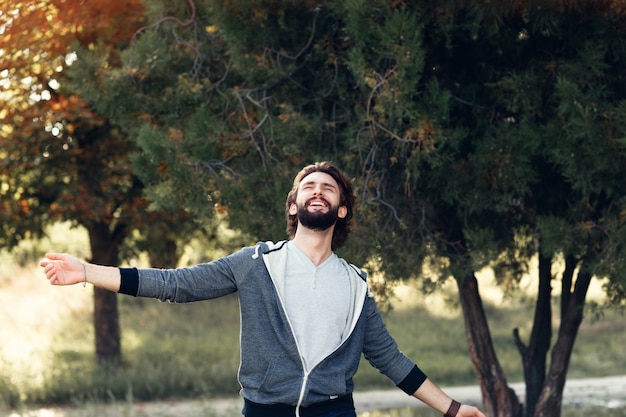 Hombre sonriente disfrutando del viento que sopla en el bosque.