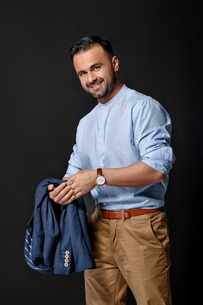 Hombre sonriente elegante hermoso en traje azul sobre fondo negro. empresario