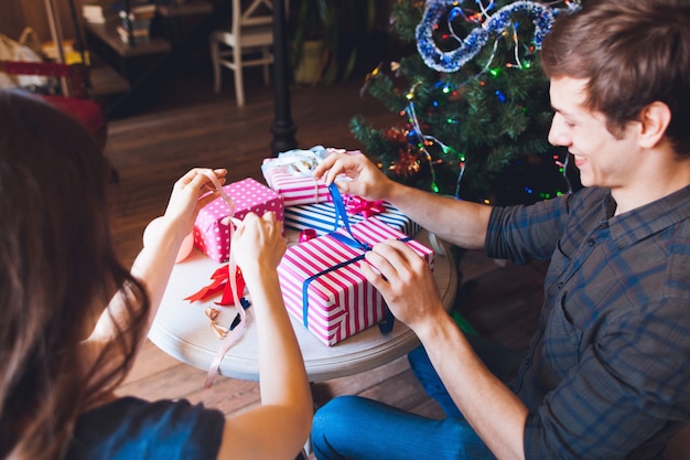 Hombre sonriente embalaje regalos con esposa.