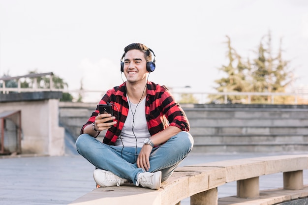 Hombre sonriente escuchando música en auriculares