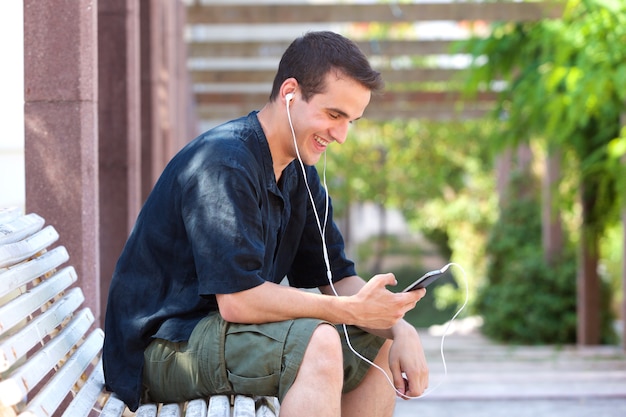 Hombre sonriente escuchando música en el teléfono celular