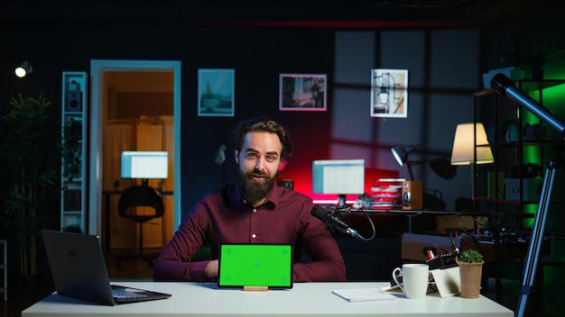 Hombre sonriente en el estudio filmando chroma key tableta revisión para entusiastas de la tecnología