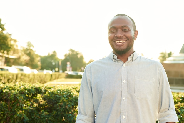 Hombre sonriente feliz al aire libre. Retrato al aire libre de sonriente joven africano en el parque.