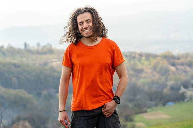 Hombre sonriente y feliz de pie en la montaña