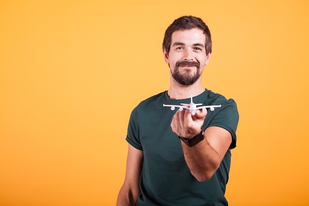 Hombre sonriente feliz que muestra un avión de juguete a la cámara en la imagen del concepto de viaje. Turismo y libertad