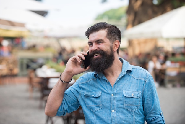 Hombre sonriente hablando con el teléfono en la calle