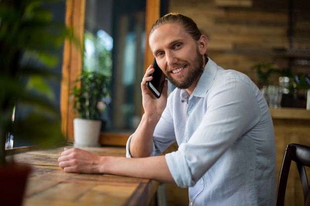 Hombre sonriente hablando por teléfono móvil en el café