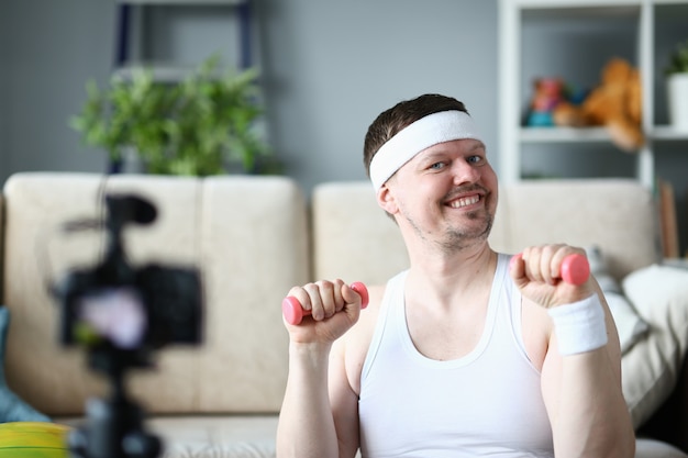 Hombre sonriente haciendo ejercicio para manos con mancuernas