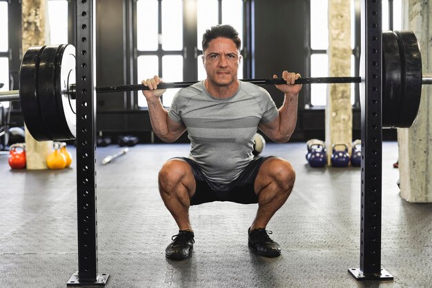 Foto hombre sonriente haciendo ejercicio con pesas en el gimnasio