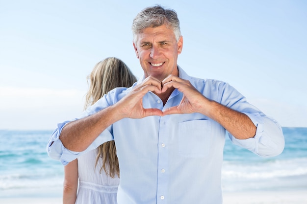 Hombre sonriente haciendo forma de corazón con sus manos