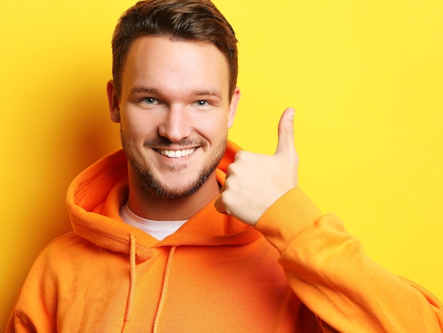 Hombre sonriente joven inteligente de pie contra el fondo amarillo