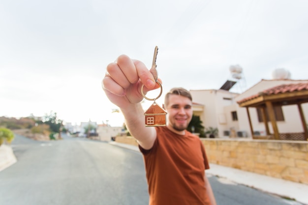 Hombre sonriente joven que muestra las claves para el concepto de apartamento y personas de bienes raíces de nueva casa