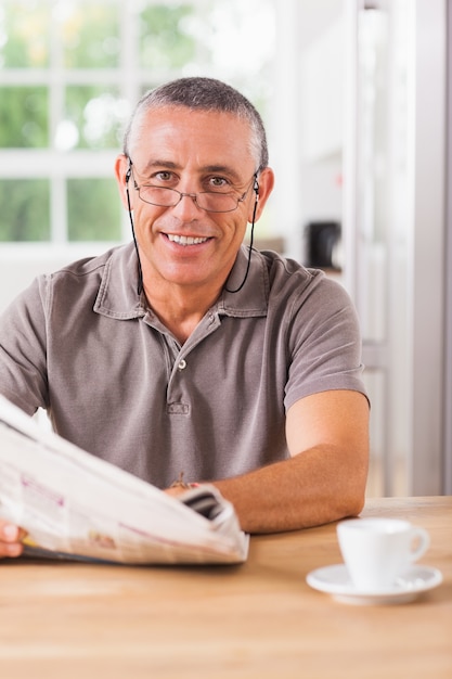 Hombre sonriente leyendo un periódico