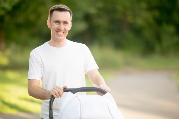 Hombre sonriente llevando un carrito de bebé