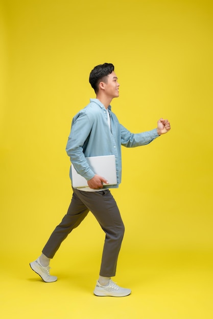 Un hombre sonriente mirando a la cámara a través de gafas de moda sosteniendo una computadora portátil cerrada