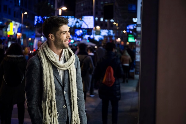 Hombre sonriente mirando en el escaparate de la noche