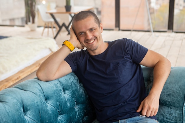 Hombre sonriente mirando a puerta cerrada sentado en el sofá en casa