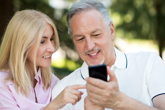 Hombre sonriente mostrando su teléfono móvil a su esposa