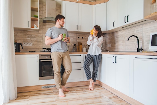 Hombre sonriente con mujer en la cocina bebiendo té amigos hablando entre ellos