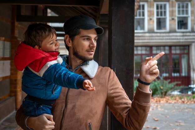 Foto hombre sonriente con un niño cortado de pie al aire libre contra el edificio