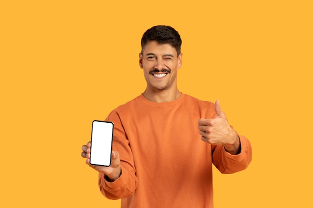 Foto hombre sonriente con el pulgar hacia arriba mostrando la pantalla de su teléfono inteligente