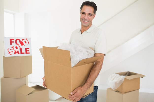 Foto hombre sonriente que lleva cajas en una casa nueva