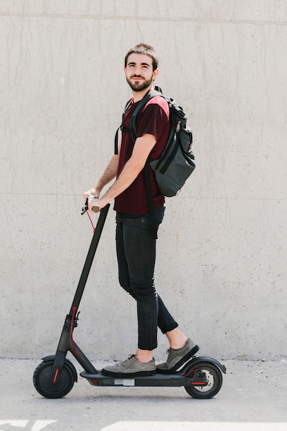 Hombre sonriente que monta un e-scooter en la calle