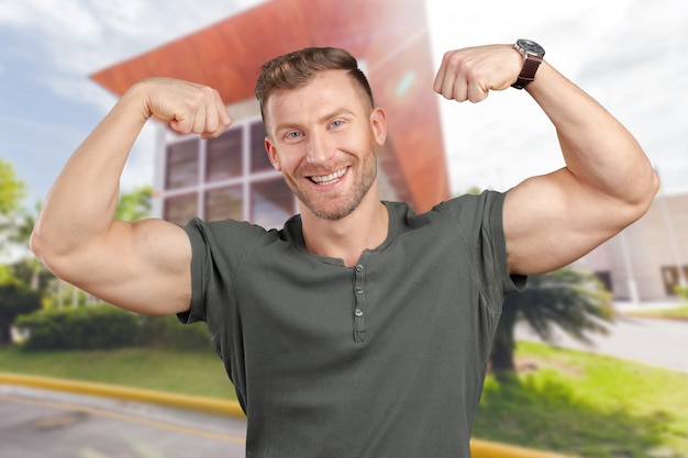 Foto hombre sonriente que muestra bíceps