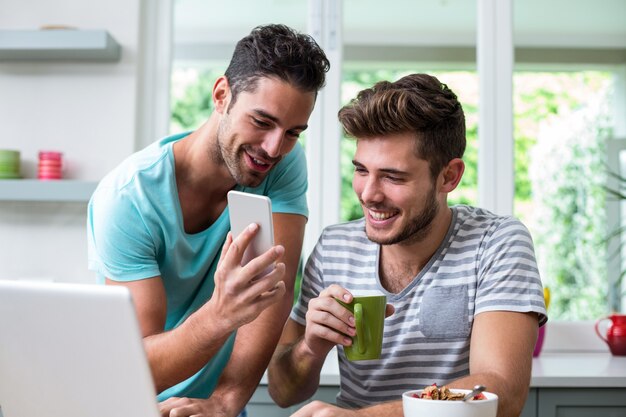 Hombre sonriente que muestra el teléfono a un amigo