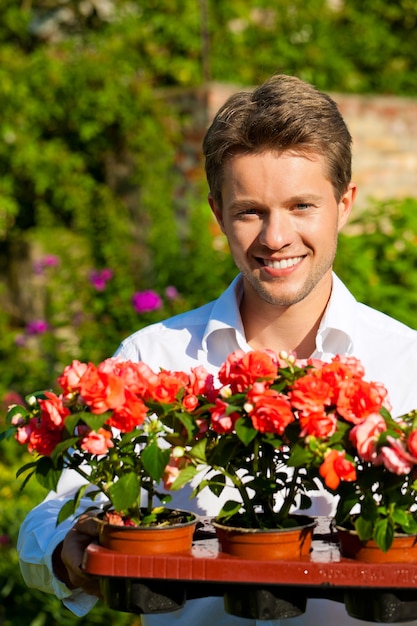 Hombre sonriente que sostiene las flores en maceta