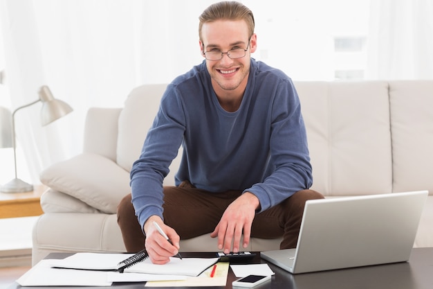 Hombre sonriente que usa la calculadora contando sus cuentas