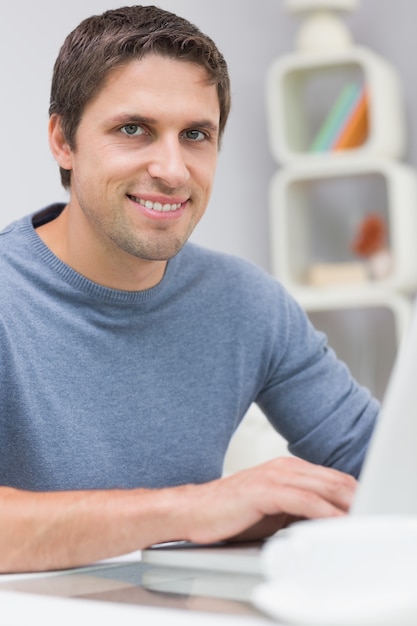 Hombre sonriente que usa la computadora portátil en la sala de estar