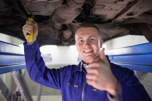 Hombre sonriente reparar un automóvil con su pulgar arriba