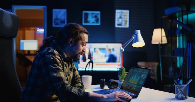 Hombre sonriente satisfecho con los datos estadísticos gráficos financieros en la pantalla de la computadora portátil