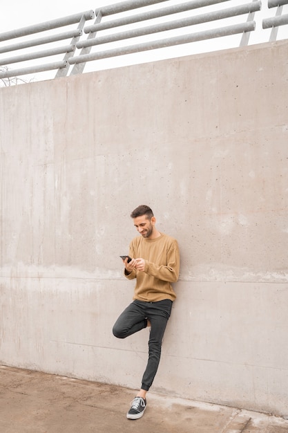 Hombre sonriente con smartphone sobre fondo gris