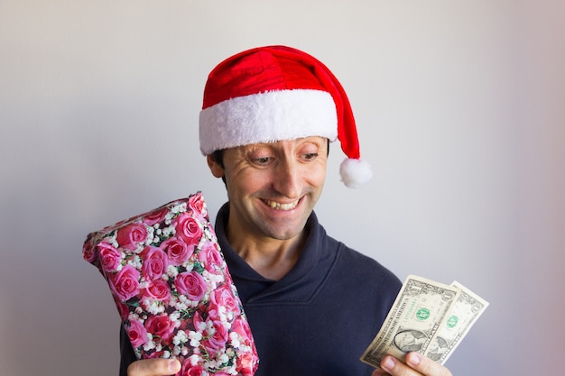 Hombre sonriente con sombrero rojo de Santa con regalo envuelto y billetes de dólar Ahorrar dinero en Navidad gif