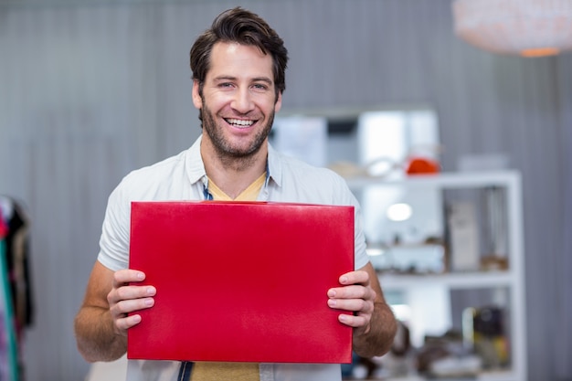 Hombre sonriente sosteniendo el cartel en blanco rojo