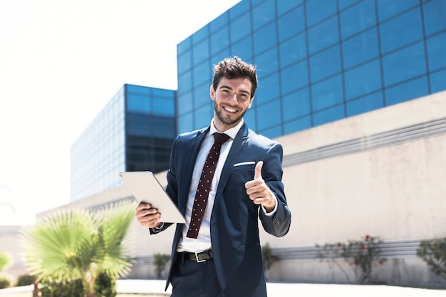 Hombre sonriente con tableta mostrando aprobación