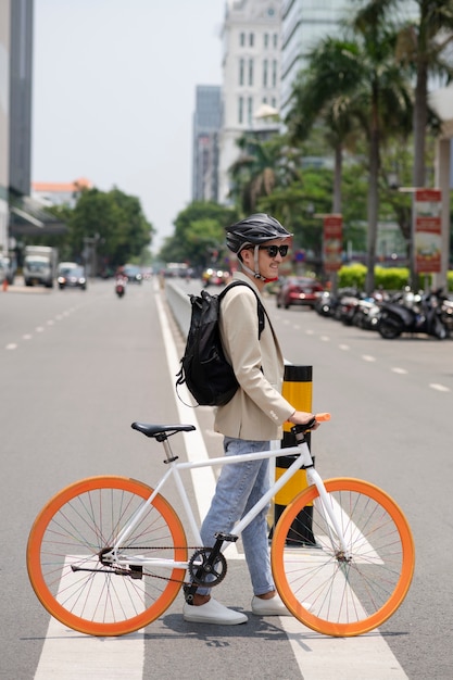 Hombre sonriente de tiro completo con bicicleta en la calle