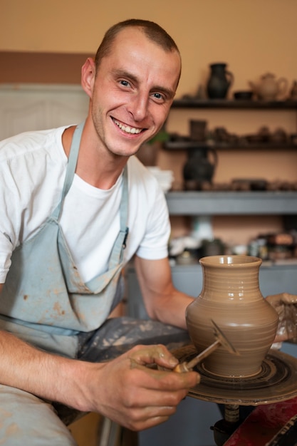 Hombre sonriente de tiro medio haciendo cerámica